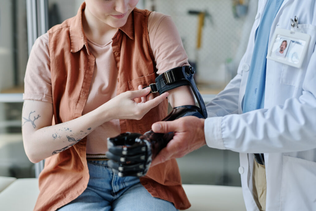 Doctor consulting young woman and fitting prosthetic arm